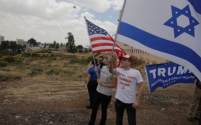 Israelis hold American and Israeli flags with the new US Embassy in the background in Jerusalem, May 14, 2018. (AP Photo/Sebastian Scheiner)