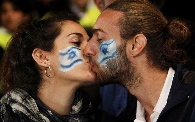 A young couple with Israeli flags painted on their cheeks kiss during an Independence Day ceremony on Mount Herzl in Jerusalem (photo credit: Miriam Alster/Flash90)