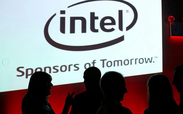 Israelis stand in front of a sign for the hi-tech company Intel. (photo credit: Moshe Shai/Flash90)