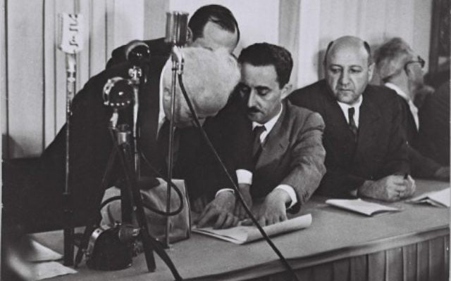 Ben Gurion (left) signing Israel's Declaration of Independence, held by Moshe Sharet, with Eliezer Kaplan looking on.