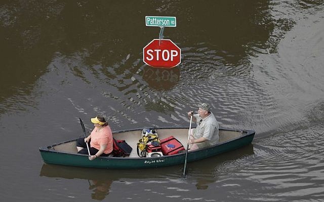 In this aerial photo, people canoe through floodwaters past a stop sign near Bear Creek Park Saturday, May 30, 2015, in Houston. (AP/David J. Phillip)