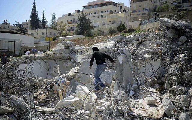 An illustrative photo of a Palestinian man climbing on rubble left after a house was demolished in the East Jerusalem neighborhood of Al-Tur on March 26, 2014, on the grounds that it was built without a construction permit. (Sliman Khader/Flash90)