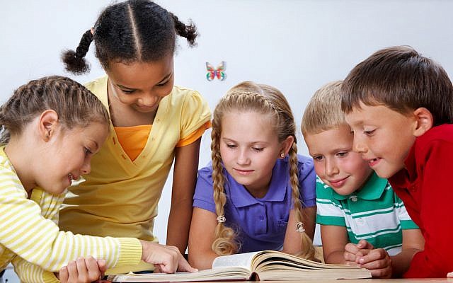 Portrait of pupils looking at page of encyclopaedia at reading lesson