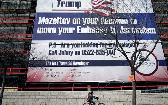 Illustrative: An Israeli child cycles past a giant banner, bearing a message of congratulations (Mazeltov) for incoming US President Donald Trump, covering a building under construction in central Jerusalem on January 20, 2017. (AFP PHOTO / Thomas COEX) Illustrative: An Israeli child cycles past a giant banner, bearing a message of congratulations (Mazeltov) for incoming US President Donald Trump, covering a building under construction in central Jerusalem on January 20, 2017. (AFP PHOTO / Thomas COEX)