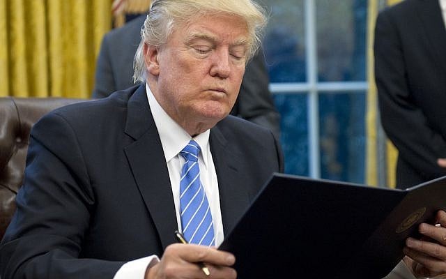 President Donald Trump reading the first of three executive orders he signed in the Oval Office, January 23, 2017. (Ron Sachs/Pool/Getty Images)