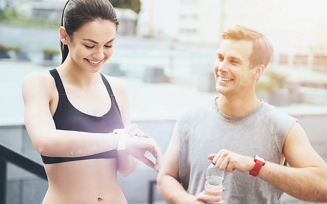Couple checking fitness trackers. (iStock)