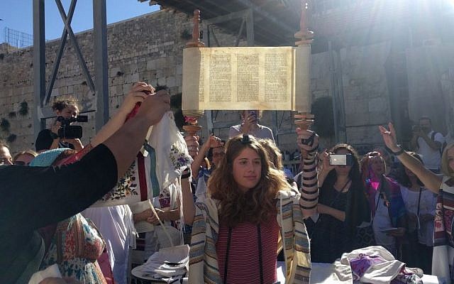 Illustrative: A young member of Women of the Wall holds up the miniature Torah scroll during the monthly Rosh Hodesh service on June 25, 2017, in the women's section of the Western Wall plaza, just before Netanyahu froze the Kotel Agreement. (Melanie Lidman/Times of Israel)