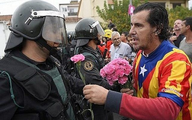 A man offers a carnation to a Spanish Guardia Civil guard in Sant Julia de Ramis, on October 1, 2017, on the day of a referendum on independence for Catalonia banned by Madrid. (AFP PHOTO / LLUIS GENE)