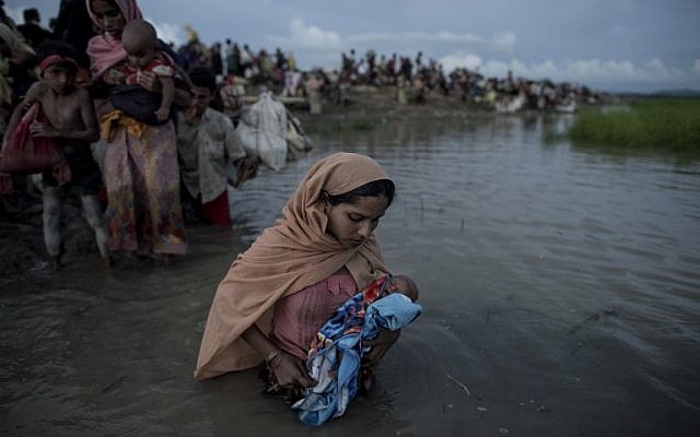 Illustrative: Rohingya refugees wading while holding a child after crossing the Naf River from Myanmar into Bangladesh in Whaikhyang on October 9, 2017. (AFP/Fred Dufour) Illustrative: Rohingya refugees wading while holding a child after crossing the Naf River from Myanmar into Bangladesh in Whaikhyang on October 9, 2017. (AFP/Fred Dufour)