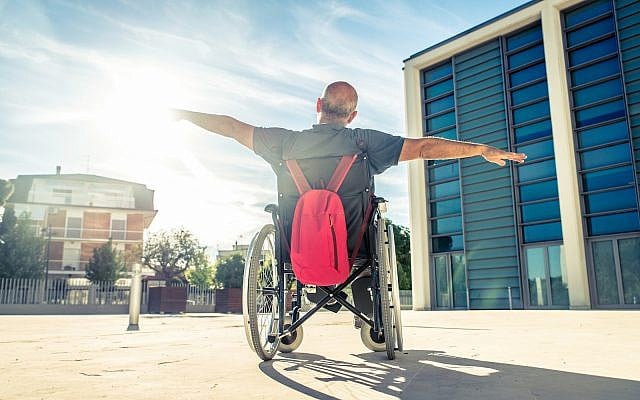 Invalid man sitting on a wheel chair and enjoying a walk outdoors