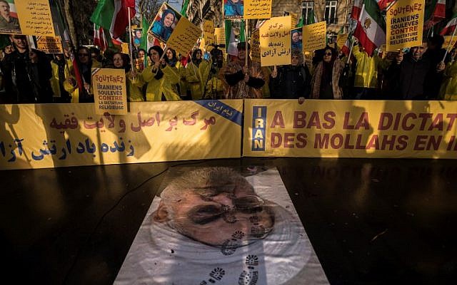 Protesters hold placards reading "Support Iranians risen up against the religious dictatorship" as they stand behind a portrait of Iranian President Hassan Rouhani with shoe marks over it during a demonstration in support of the Iranian people amid a wave of protests spreading throughout Iran, on January 3, 2018, in Paris.(AFP PHOTO / Lionel BONAVENTURE)