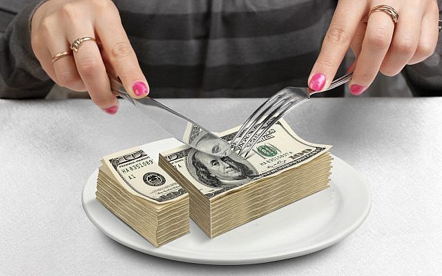 US taxes, dollars, hands cut money on plate, reduce funds concept. (via iStock)