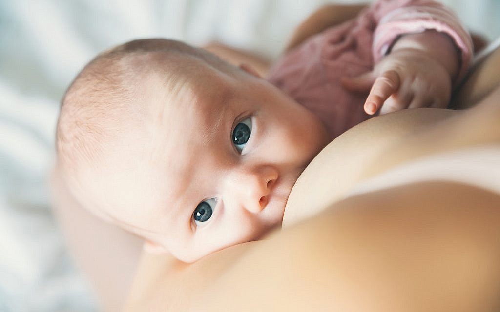 Baby eating mother's milk. Mother breastfeeding baby. Beautiful mom breast feeding her newborn child. Young woman nursing and feeding baby. Concept of lactation infant.