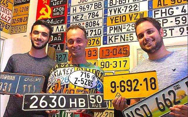 Israeli license plate collectors, displaying their favorite examples from Jordan, Russia, Israel and Swaziland, gather at the Ness Ziona home of Yoav Katz, far right, to talk shop. (Larry Luxner)