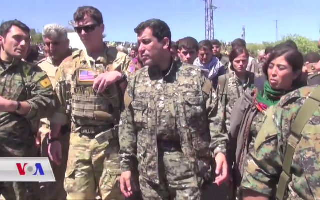 An unidentified US military officer accompanies YPG and YPJ officers visiting a town in the northeastern Hasaka Governorate during the aftermath of Turkish airstrikes in the area. (Wikipedia) An unidentified US military officer accompanies YPG and YPJ officers visiting a town in the northeastern Hasaka Governorate during the aftermath of Turkish airstrikes in the area. (Wikipedia)