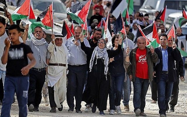Illustrative. Palestinian wave flags during a demonstration at the West Bank Bedouin village of Khan al-Ahmar over Israel's plans to demolish it, on October 19, 2018. (Ahmad Gharabli/AFP) Illustrative. Palestinian wave flags during a demonstration at the West Bank Bedouin village of Khan al-Ahmar over Israel's plans to demolish it, on October 19, 2018. (Ahmad Gharabli/AFP)