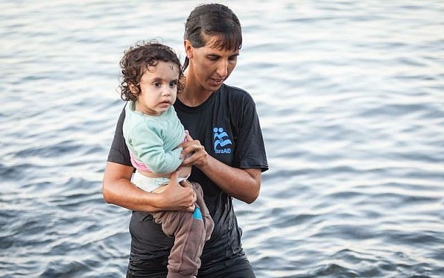 Illustrative. Tali Shaltiel, an Israeli physician, taking a Syrian child from a dinghy that arrived at a beach on the Greek island of Lesbos. (Boaz Arad/IsraAID)