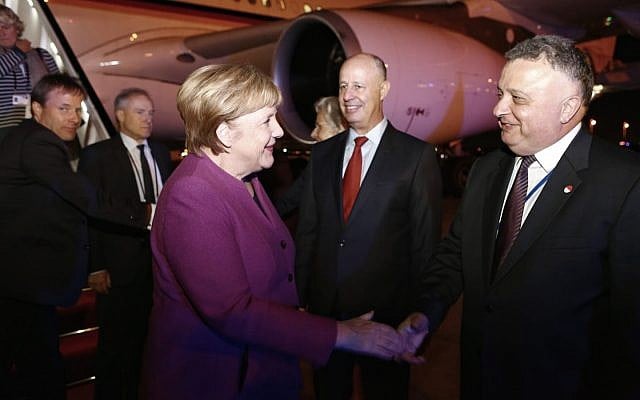 German Chancellor Angela Merkel shakes hands with Israeli Ambassador to Germany Jeremy Issacharoff at Ben Gurion Airport on October 3, 2018, as Minister Tzachi Hanegbi looks on. (Avi Davidi/Foreign Ministry)