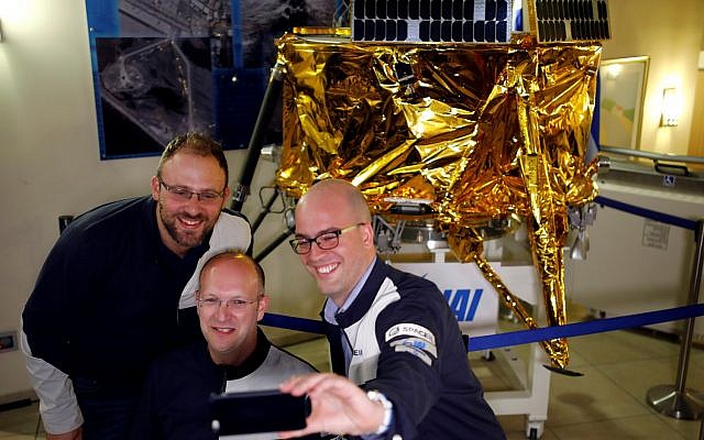 Members of Israeli non-profit group SpaceIL and representatives from Israel Aerospace Industries (IAI) do a selfie in front of a model of Beresheet spacecraft, near the control room, in Yahud, Israel April 11, 2019 (REUTERS/Amir Cohen) [For use by Michael Laitmen, by arrangement]