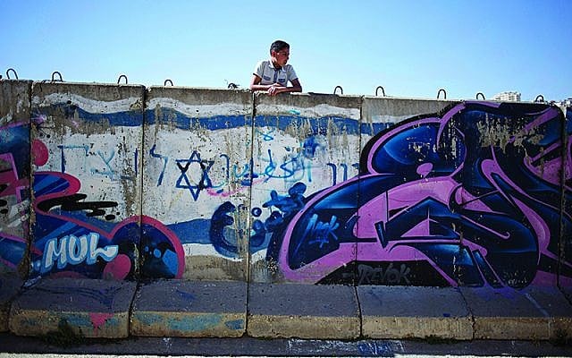 A Palestinian boy looks behind a wall separating Jewish  (Jewish News AP Photo/Ariel Schalit)