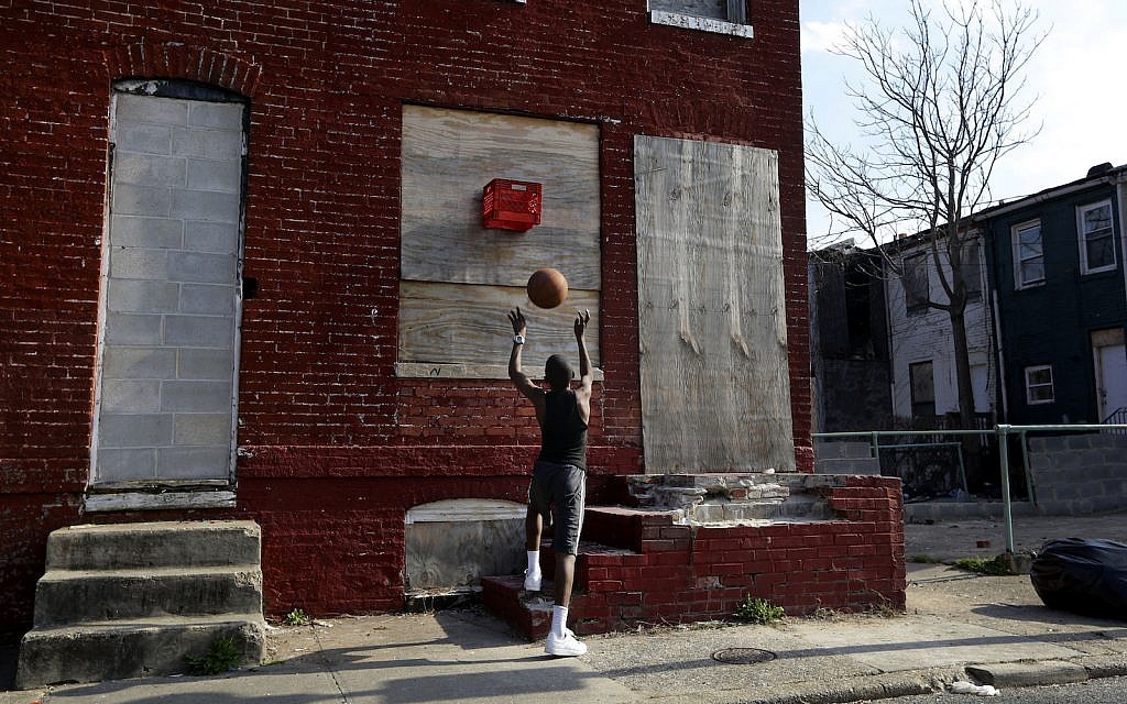 A boy shoots a basketball into a makeshift basket made from a milk crate and attached to a vacant row house in Baltimore. In 2013, an estimated 16,000 buildings were vacant or abandoned in Baltimore. April 8, 2013 (AP Photo/Patrick Semansky)