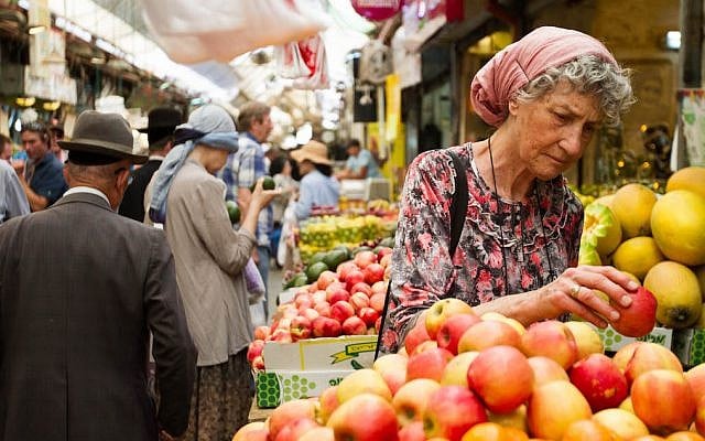 Illustrative. A woman picks out apples at the Mahane Yehuda market in Jerusalem on June 16, 2015. (Micah Bond/FLASH90)