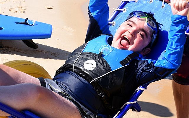 Adi Goldschmiedt, who has Duchenne muscular dystrophy, sports a huge smile after “catching a wave” off the coast of Bat Yam, south of Tel Aviv. (Larry Luxner) Adi Goldschmiedt, who has Duchenne muscular dystrophy, sports a huge smile after “catching a wave” off the coast of Bat Yam, south of Tel Aviv. (Larry Luxner)
