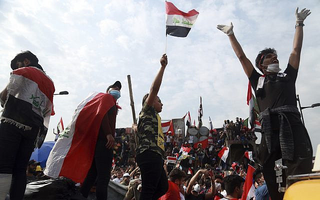 Anti-government protesters stand on barriers set up  by Iraqi security forces to close the Joumhouriya Bridge leading to the Green Zone government area, in Baghdad, Iraq, Sunday, Nov. 3, 2019. (AP Photo/Hadi Mizban)