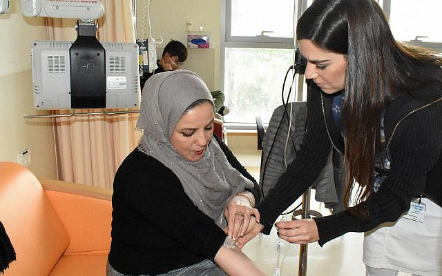 Keren Sztrigler (right), a nurse at Jerusalem's Shaare Zedek Medical Center, administers Cerozyme — an enzyme replacement therapy — to Rania Qwaider, a Palestinian woman from Ramallah with Gaucher disease. (Larry Luxner)