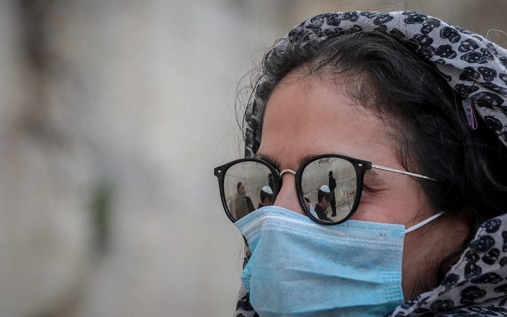 Illustrative: A woman wears face mask for fear of the coronavirus as she attends a bar mitzvah, at the Western Wall, Judaism's holiest site, in Jerusalem's Old City on March 19, 2020. (Yossi Zamir/Flash90) Illustrative: A woman wears face mask for fear of the coronavirus as she attends a bar mitzvah, at the Western Wall, Judaism's holiest site, in Jerusalem's Old City on March 19, 2020. (Yossi Zamir/Flash90)