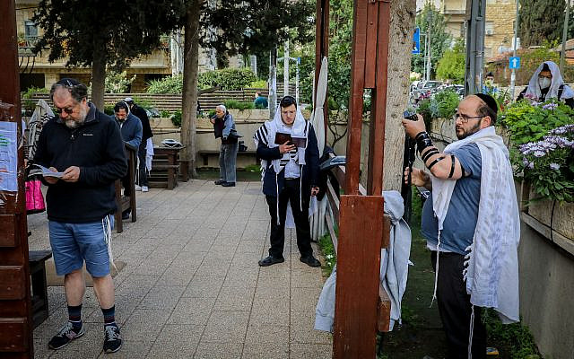 Illustrative. Jewish men pray outside a synagogue at the Nachlaot neighborhood in Jerusalem, on March 25, 2020 (before masks were required by law). (Yossi Zamir/Flash90)
