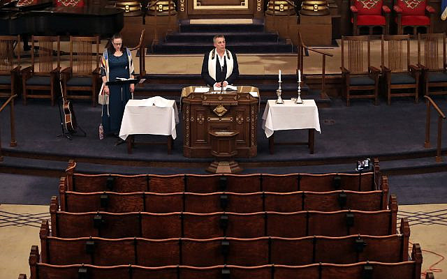 Illustrative: Rodef Shalom Rabbi Aaron Bisno, center, delivers his sermon with soloist Molly May, left, during an Erev Shabbat service that is being streamed live on Facebook. Friday, March 20, 2020. (AP Photo/Gene J. Puskar)