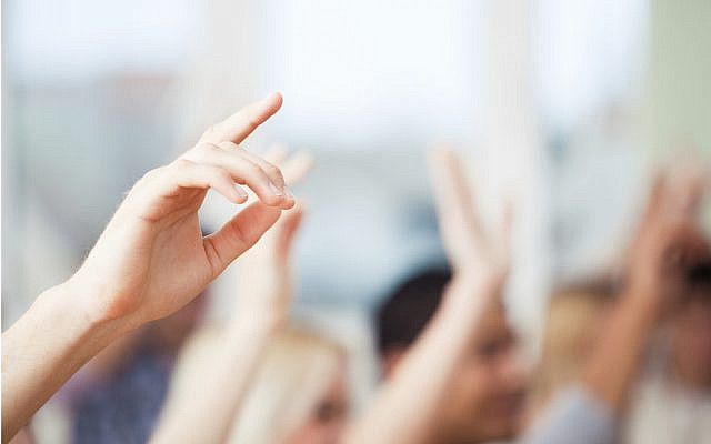 A group of students raising their hands in class.