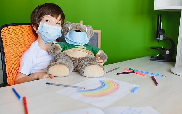 Kid in mask painting rainbow at home during coronavirus pandemic concept. Let's all be well. Stay at home Social media campaign. Children Chase the rainbow