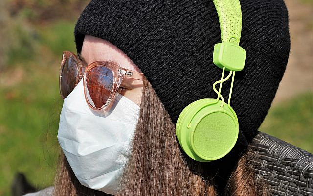A woman wearing a protective mask with headphones (Pixaby/ivabalk)