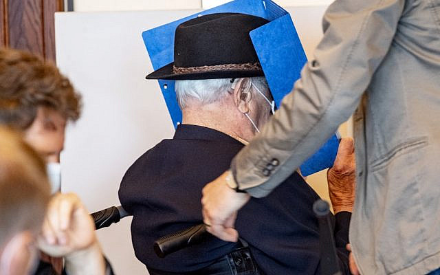 Bruno Dey, a former SS-watchman at the Stutthof concentration camp, hides his face behind a folder as he arrives on a wheelchair for a hearing in his trial on July 20, 2020, in Hamburg, northern Germany. (Axel Heimken / POOL / AFP)