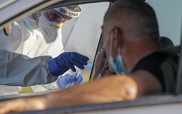 Illustrative. A Magen David Adom paramedic swabs a person for COVID-19 at a drive-thru testing site in the central city of Lod on July 15, 2020. (Ahmad Gharabli/AFP)