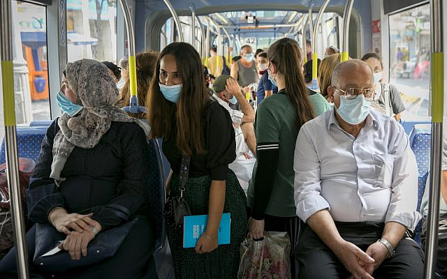 Passengers wearing face masks for fear of the coronavirus ride the light rail in in Jerusalem on April 21, 2020 (Olivier Fitoussi/Flash90)