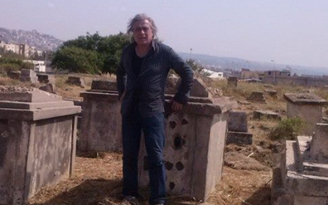 Caretaker of the Sidon Jewish cemetery Nagi Zeidan stands in front of a tombstone riddled with bullet holes (Photo: courtesy)