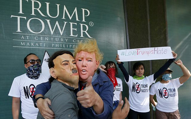 Protesters, with one wearing a Donald Trump mask and another with an Adolf Hitler mask, embrace as others display a #lovetrumpshate hashtag during a brief picket at the Trump Tower hours after Trump was sworn in as the 45th President of the United States Jan. 21, 2017 in the financial district of Makati city east Manila, Philippines.(AP Photo/Bullit Marquez) Protesters, with one wearing a Donald Trump mask and another with an Adolf Hitler mask, embrace as others display a #lovetrumpshate hashtag during a brief picket at the Trump Tower hours after Trump was sworn in as the 45th President of the United States Jan. 21, 2017 in the financial district of Makati city east Manila, Philippines.(AP Photo/Bullit Marquez)