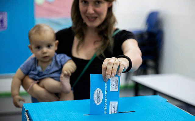 A woman holds her baby as she casts her ballot at a voting station in Jerusalem, during the Knesset Elections, on September 17, 2019. (Yonatan Sindel/Flash90)