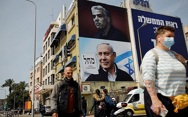 People walk near a Likud party election campaign banner depicting Israeli Prime Minister Benjamin Netanyahu and his challenger, Yesh Atid party leader Yair Lapid, ahead of the March 23 ballot, in Tel Aviv, Israel March 14, 2021. REUTERS/Corinna Kern People walk near a Likud party election campaign banner depicting Israeli Prime Minister Benjamin Netanyahu and his challenger, Yesh Atid party leader Yair Lapid, ahead of the March 23 ballot, in Tel Aviv, Israel March 14, 2021. REUTERS/Corinna Kern