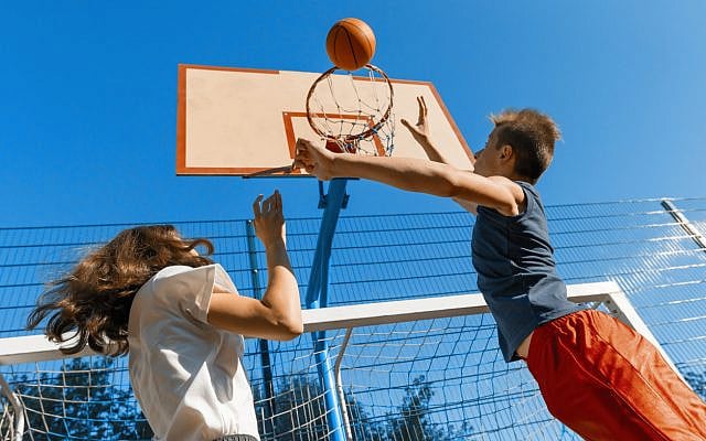 Illustrative. A girl and a boy shoot hoops. (iStock)
