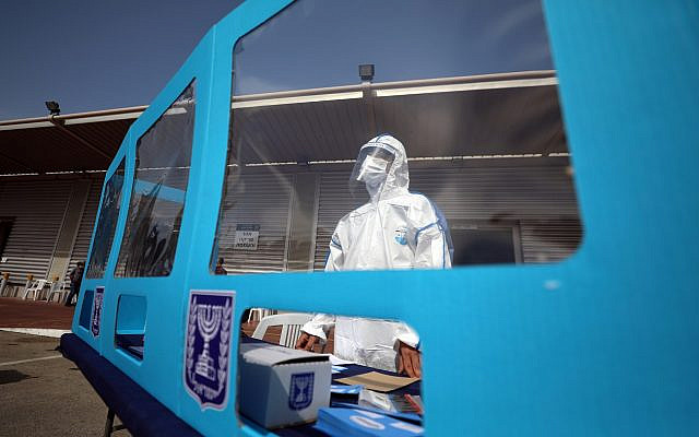 An employee wearing personal protective equipment (PPE) stands behind a booth during a demonstration for the media revealing preparations ahead of Israel's upcoming election amid the coronavirus disease (COVID-19) crisis, at the Central Elections Committee's logistics centre in Shoham, Israel February 23, 2021. REUTERS/Ammar Awad