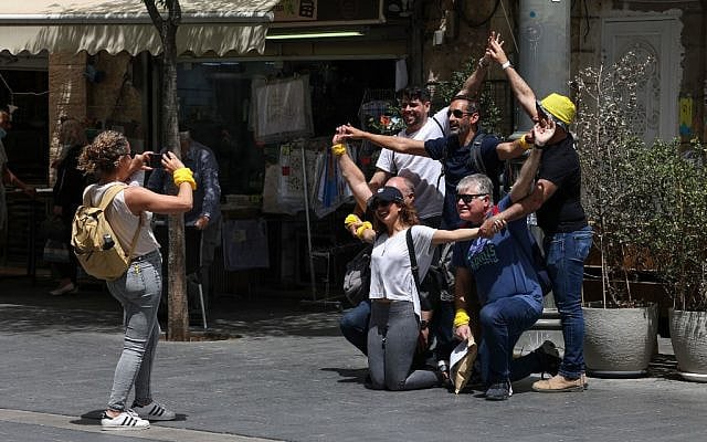 People pose for a picture on a street in Jerusalem, on April 18, 2021, after Israeli authorities announced that face masks for COVID-19 prevention were no longer required outdoors. (Menahem Kahana / AFP)
