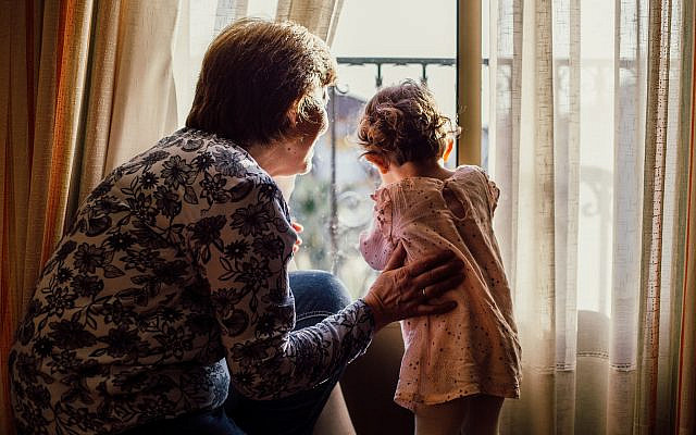 A beautiful shot of an elderly female and a baby girl looking through a window