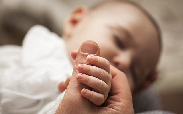 A newborn holding onto an adult's thumb. (iStock)