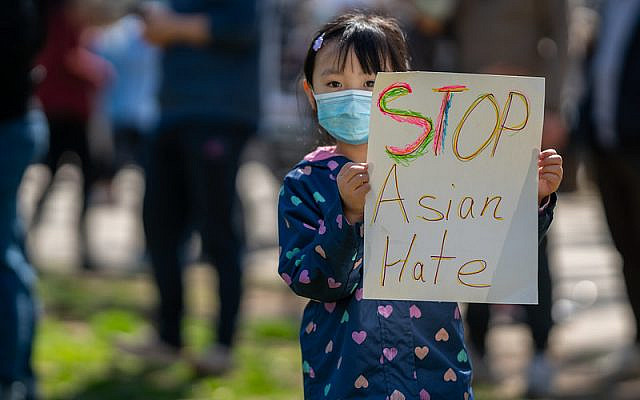 Asian girl holding a stop asian hate sign at a rally.