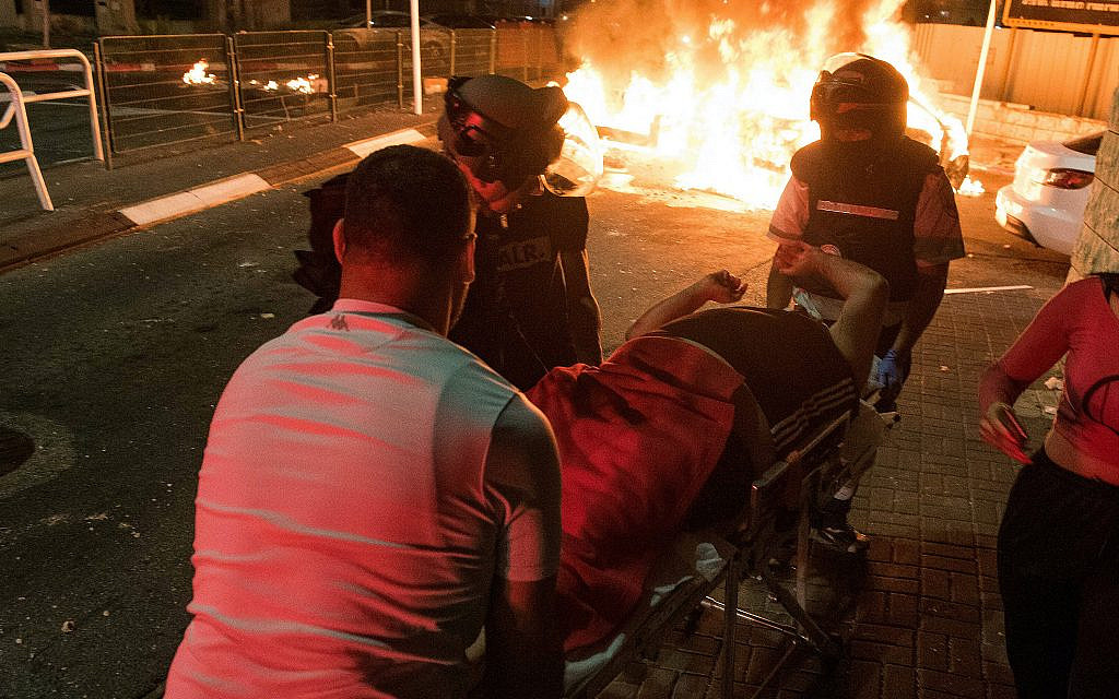 Medics evacuate an injured man during clashes between Arab and Jews in Acre, northern Israel, May 12, 2021. (Roni Ofer/ Flash90)