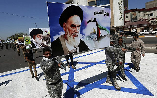 In this photo from June 23, 2017, supporters of Iraqi Hezbollah brigades march on a representation of an Israeli flag with a portrait of late Iranian leader Ayatollah Khomeini and Iran's Supreme Leader Ayatollah Ali Khamenei, in Baghdad, Iraq. (AP Photo/Hadi Mizban, File)